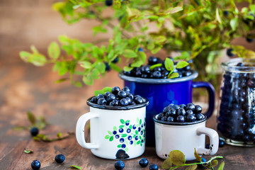 Fresh ripe bluberries (bilberries) in enamel mugs