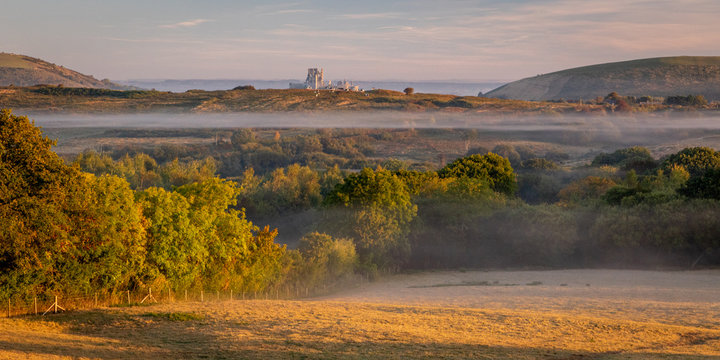 Beautiful morning mist over fields and castle ruin