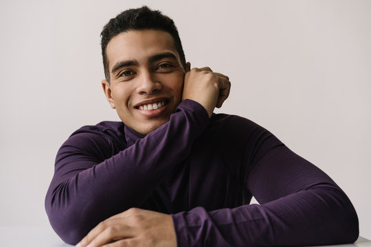 Authentic portrait of successful handsome African American business man with happy emotional face wearing stylish turtleneck posing for pictures in light studio isolated on white background