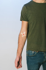 Cropped view of patient in green t-shirt and blue jeans with plasters, blood donation concept