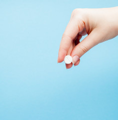 Close-up shot of pill in nurse's hand isolated over blue background. Copy space