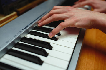 Fototapeta na wymiar Hands of a man playing the piano in the studio.