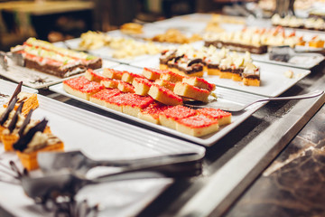 Assortment of fresh desserts displayed in hotel buffet. Variety of cakes in canteen ready for dinner