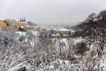 Fototapeta premium Snowy foggy Prague City with gothic Castle from Hill Petrin, Czech republic