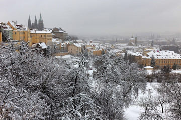 Obraz premium Snowy foggy Prague City with gothic Castle from Hill Petrin, Czech republic