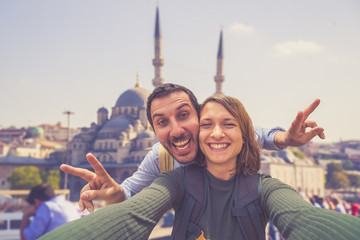 Happy young couple taking a selfie photo in Istanbul, Turkey. Two smiling tourists with smart phone...