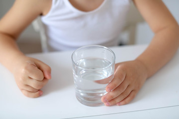 Cute smiling boy with glass of water isolated on a white background