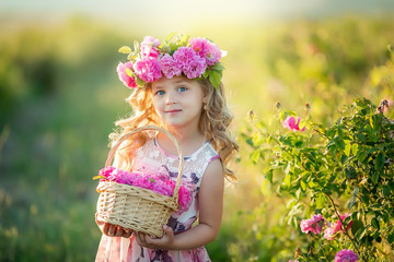 A little girl with beautiful long blond hair, dressed in a light dress and a wreath of real flowers...