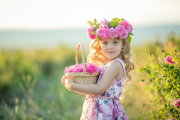 A little girl with beautiful long blond hair, dressed in a light dress and a wreath of real flowers...