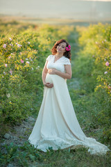 Fototapeta na wymiar Outdoor natural portrait of beautiful pregnant woman in white dress