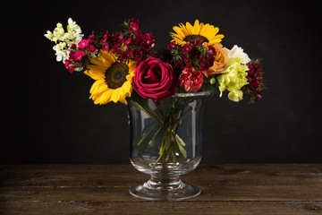 Bouquet of white yellow and red flowers in a vase on a dark background