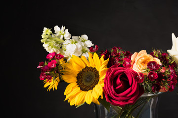 Bouquet of white yellow and red flowers in a vase on a dark background