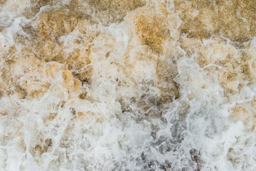 Raging sea surf close-up. Abstract background. Sea foam on the sandy shore.