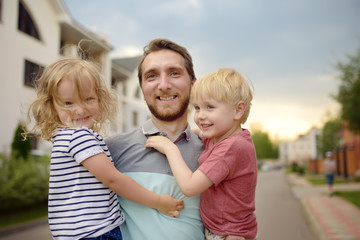 Fototapeta premium Young happy father with two cute little children walking in summer.