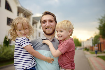 Young happy father with two cute little children walking in summer.