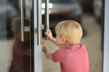 Little boy opens the glass door of the entrance