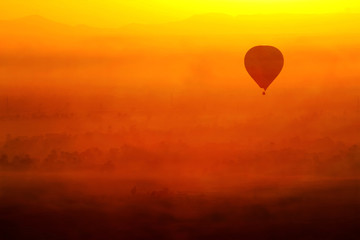 hot air balloon in the sky in Luxor, Egypt. In a beautiful sunrise with foggy orange background.