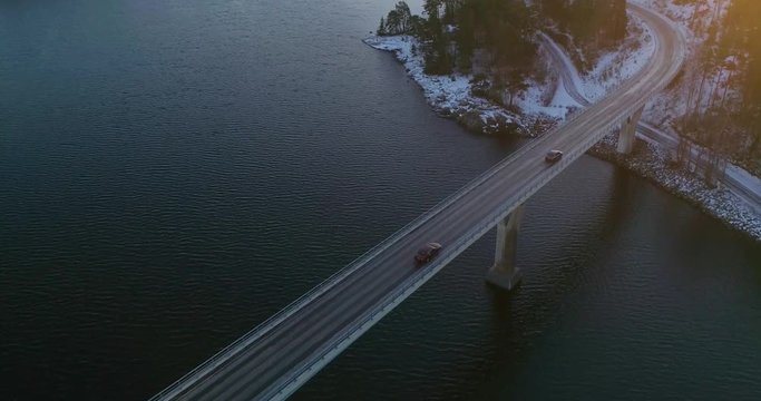 Car on a bridge, C4k aerial, rising, drone shot, following a vehicle driving on a road connecting islands, in finnish archipelago, at sunset, on a autumn evening, Varsinais-Suomi, Finland