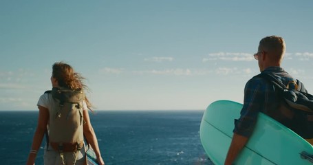 Attractive couple out adventuring together in gold fields by the sea, summer surf adventure camping, slow motion