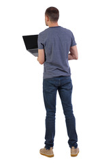 Back view of a man who is standing with a laptop.