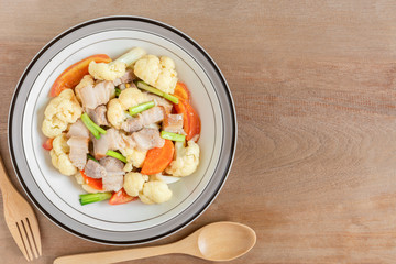 top view of stir fried pork belly and vegetable with soy sauce in a ceramic dish. homemade style food concept.