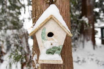 birdhouse covered in winter snow on a tree