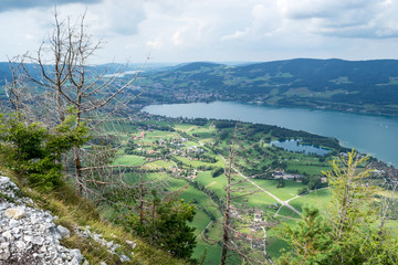 Naklejka na ściany i meble Mondsee lake in Austria with green fields and clouds, as seen from above on a bright, Summer day. Top holiday location near Salzburg.