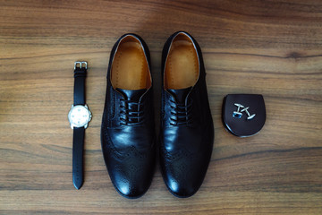 Men's leather shoes, watches and cufflinks on the background of a brown table. Clothing accessories businessman. Concept of grooms accessories at wedding day.