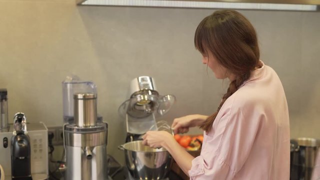 The mother takes out the dough from the mixer using a spoon. In a meantime, her eldest daughter observes her mother and learns cooking.