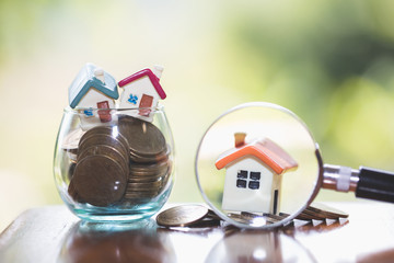 concept of a mortgage, a coin, a model of a house and a magnifying glass, house and money. magnifying glass and coins, construction, rental housing.