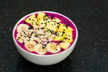 Smoothie bowl with pieces of banana, mango and cashew nuts for topping
