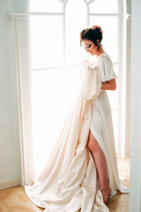 Fototapeta premium Elegant brunette in silk peignoir sitting at the dressing table
