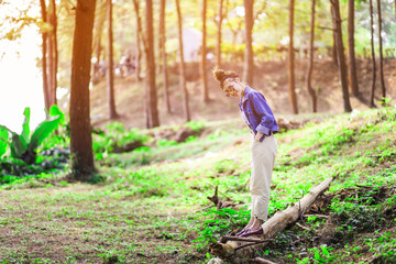 Beautiful Asian woman in the pine wood wearing jean jacket