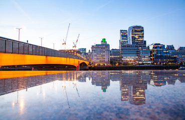 london bridge and skyscrapers reflecting at night