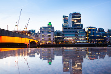 london bridge and skyscrapers reflecting at night
