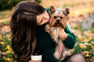 Beautiful woman walk with dog and drink coffee in the park.