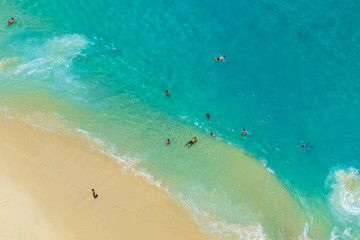 BALI, INDONESIA - 3rd FEB 2019; Aerial view of people swimming in the transparent turquoise sea over sunny day at Kelingking beach. Top view from cliff.
