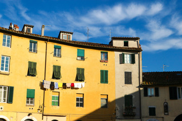 Traditional italian yellow medieval house with dry linen on the rope in bright winter morning, Lucca, Tuscany, Italy