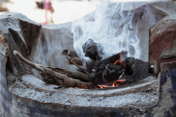 Fire and decorative smoke cloud from burning charcoal grill and firewood in Thai tradition Clay stove.
