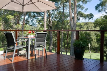 Table and chairs with umbrella on sunny deck overlooking golf course