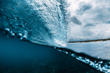 Fototapeta na wymiar Blue barrel wave in ocean. Breaking wave and cloudy sky