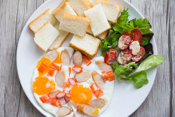 plate of fried eggs with sausage and vegetables on wooden table