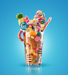 Monster shake, freak caramel shake isolated. Colourful, festive milk shake cocktail with sweets, jelly. Colored caramel milkshake array of different childs sweets and treats in glass on white