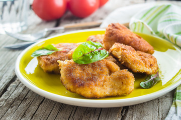 Homemade Sliced Wiener Chicken Schnitzel on plate on wooden table background.