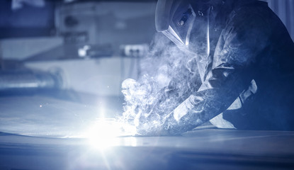 Fototapeta na wymiar Professional welder performs welding work on metal in protective mask. Industrial worker concept