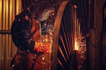 Professional welder performs welding work on metal in protective mask. Industrial worker concept