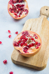 Two half pomegranate fruit lay on wooden board on blue table background, close up