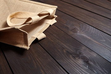 Reusable shopping bag, natural textile fiber, eco hessian or jute sack on brown wooden table