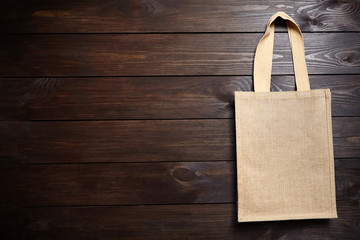 Reusable shopping bag, natural textile fiber, blank eco hessian or jute sack on brown wooden...