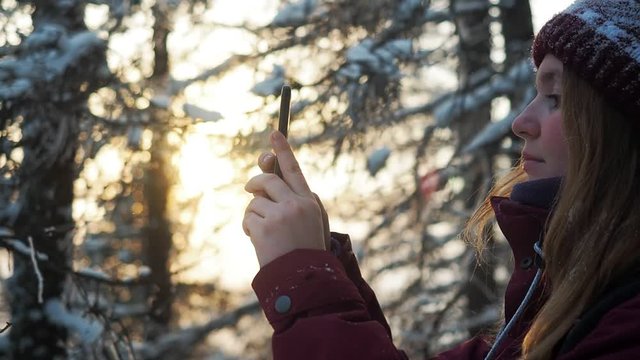 Close up from the back of girl or woman taking photo of sunset view landscape with her phone. Tourist travel in winter take photo of beautiful nature. Sunset in mountain forest.